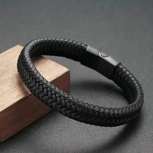 Black braided leather bracelet on a dark surface with a wooden block