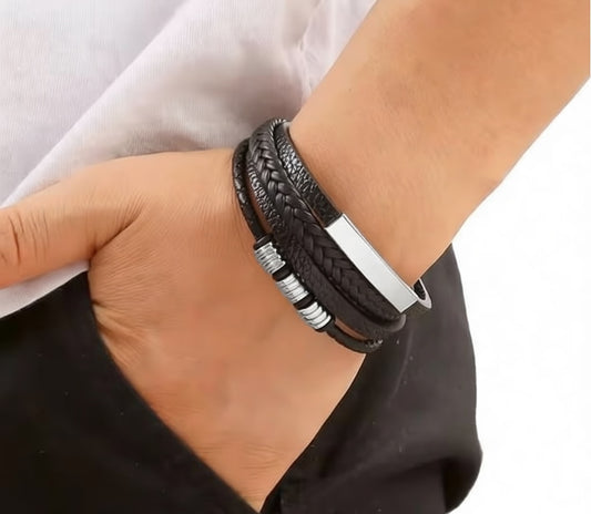 Black braided leather bracelet with silver accents on a wrist against a neutral background