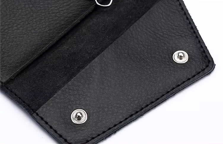 Close-up of a black leather wallet with metal rivets on a white background