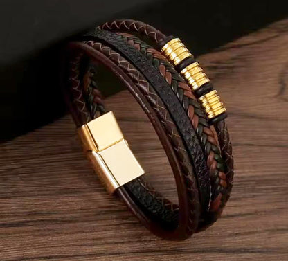 Brown braided leather bracelet with gold accents on a wooden surface