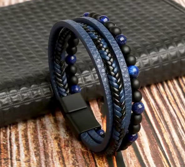 Multistrand bracelet with blue and black beads and leather straps on a textured surface