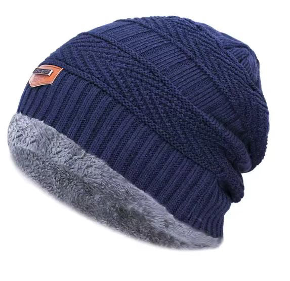 Navy blue knit beanie with gray fleece lining on a white background