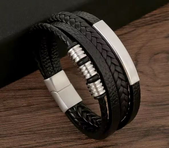 Black braided leather bracelet with silver accents on a wooden surface