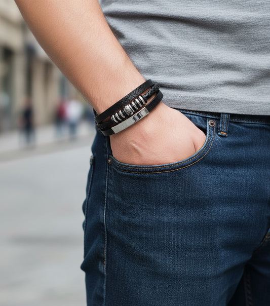 Person wearing a black leather bracelet with metal accents on a blurred street background