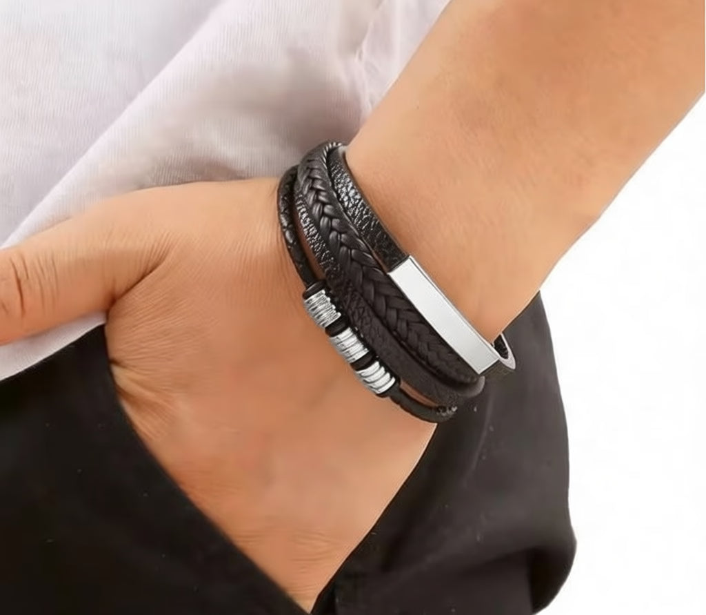 Black braided leather bracelet with silver accents on a wrist against a neutral background