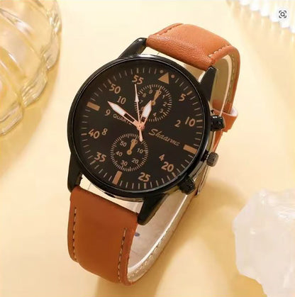 Wristwatch with brown leather strap and black dial on a light yellow background