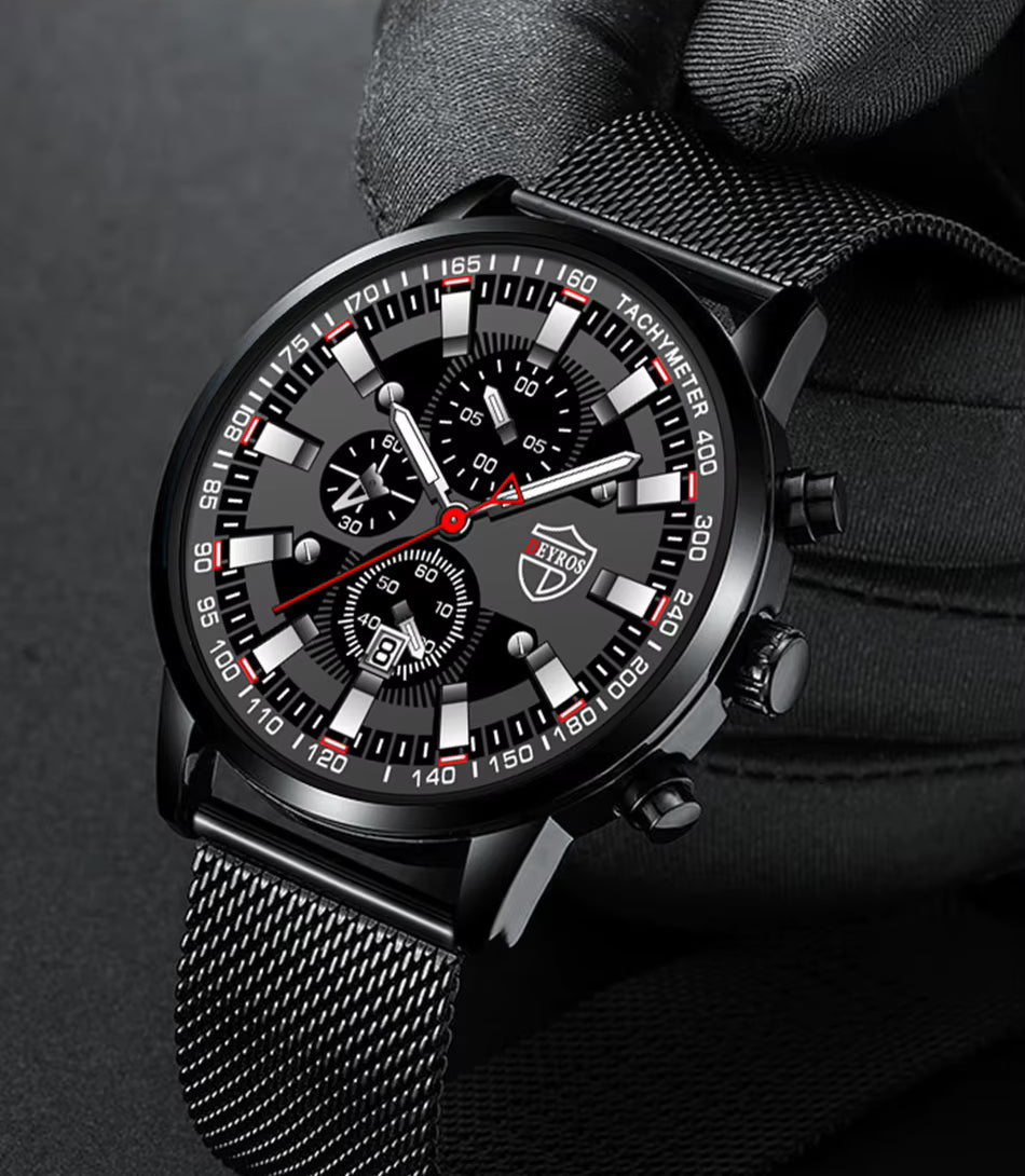 Black wristwatch with detailed face held by a gloved hand on a dark background