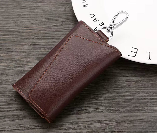 Brown leather key case with a keychain on a wooden surface