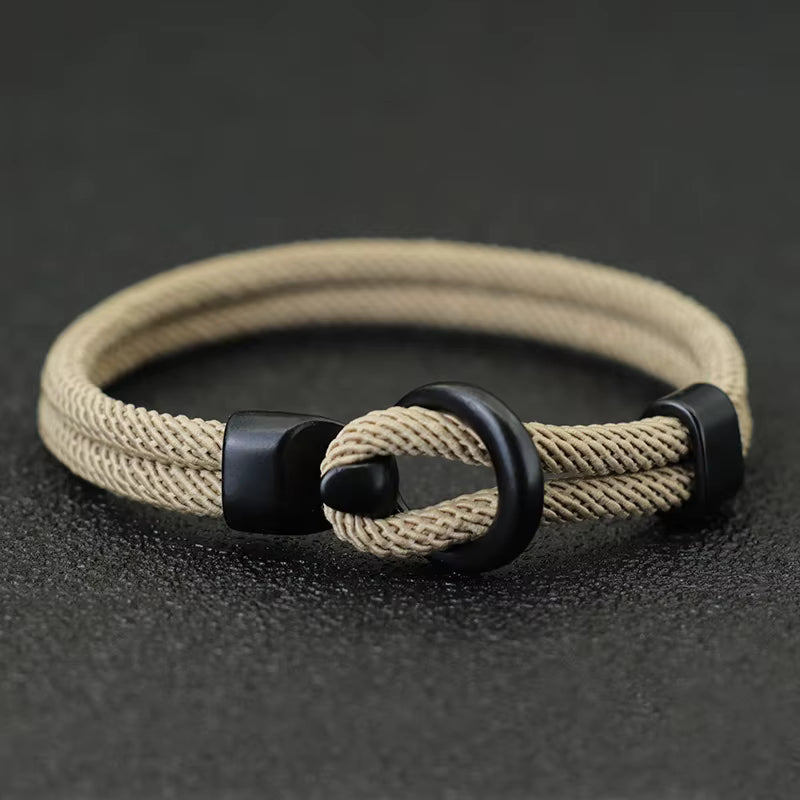 Khaki braided bracelet with black metal clasp on a dark background