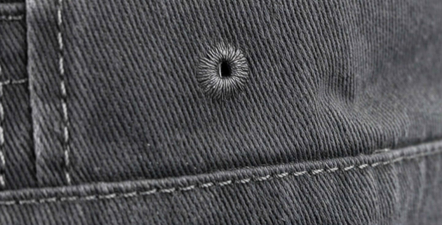 Close-up of a bullet hole on grey denim fabric