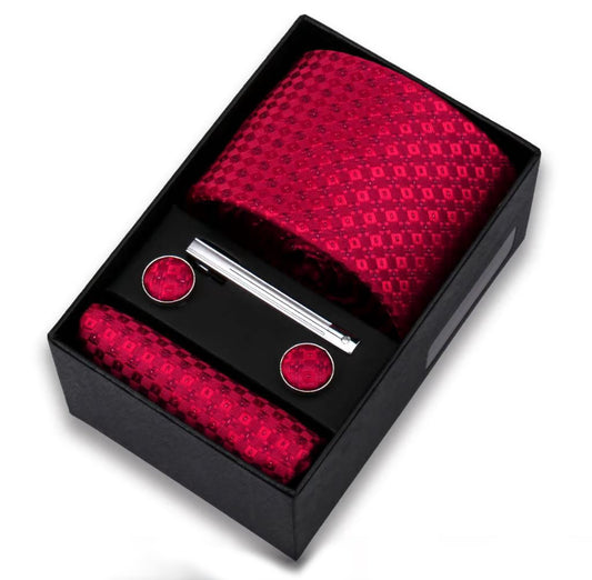 Red patterned tie, pocket square, tie clip and cufflinks set in a black box on a white background