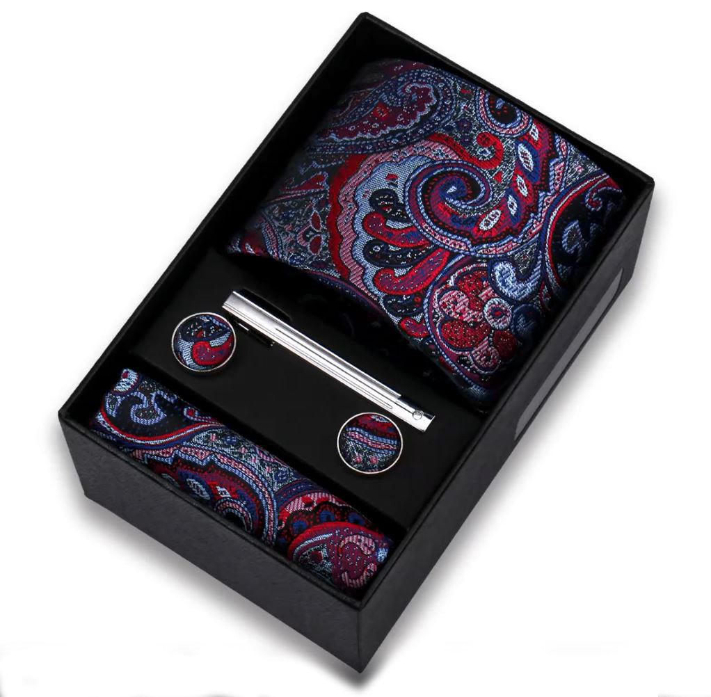 Paisley patterned tie, pocket square, and cufflinks set in a black box on a white background