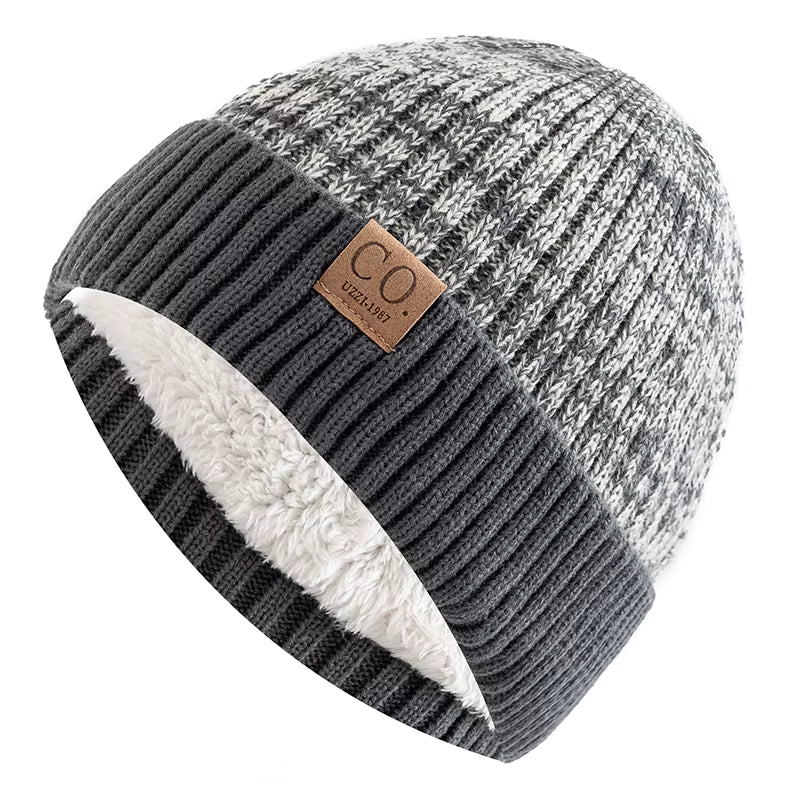 Knitted beanie with grey and white pattern, brown leather label, and white interior on a white background